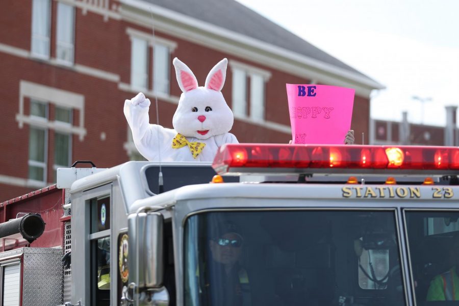 The Easter Bunny waves to kids from the top of the fire truck while riding past Dixon Hall on Saturday, April 11, 2020.