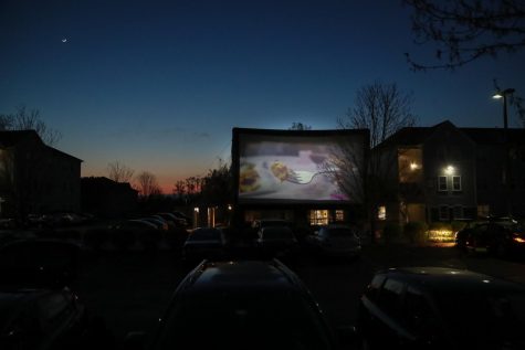 The movie Night School is projected onto a large outdoor screen at Vulcan Village.