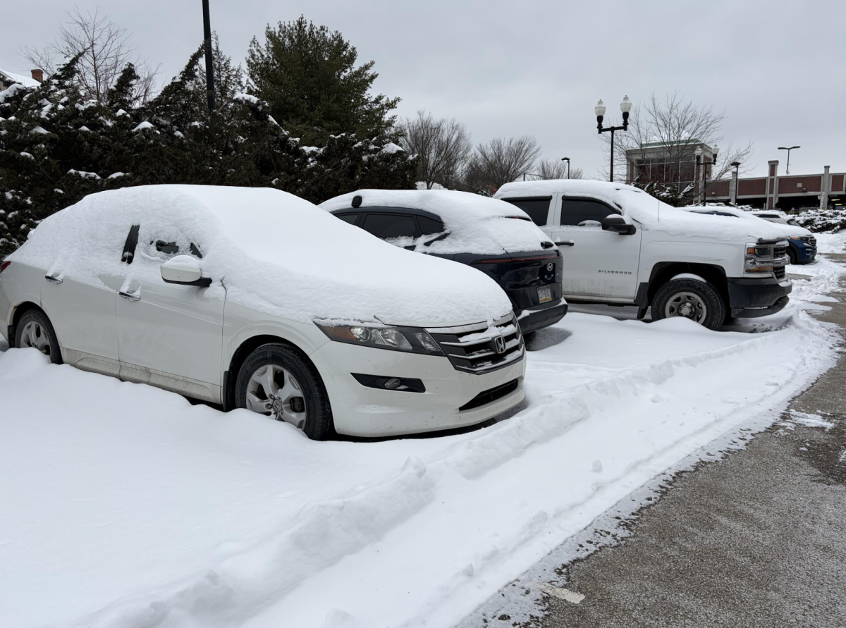 Several cars sit covered with snow in the parking lot outside Smith Hall. 
