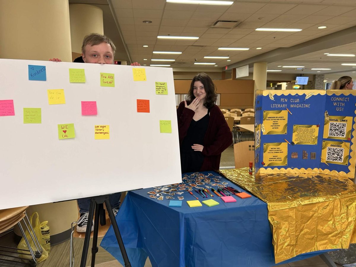 Pen Club's Treasurer, Michael (left) and Secretary, Violet (right) posing behind the club's table in Natali student Center