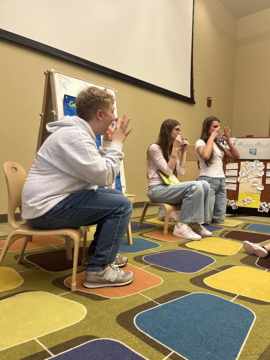 Gavin Barrett (left), Linette Pierce (center), and Rylee Baukol (right) teaching Easter-themed sign language to preschool students